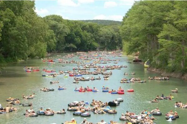 A river with numerous people floating in tubes.