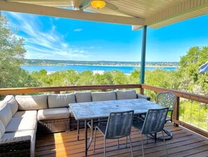 A covered outdoor seating area with a view of a body of water and greenery.