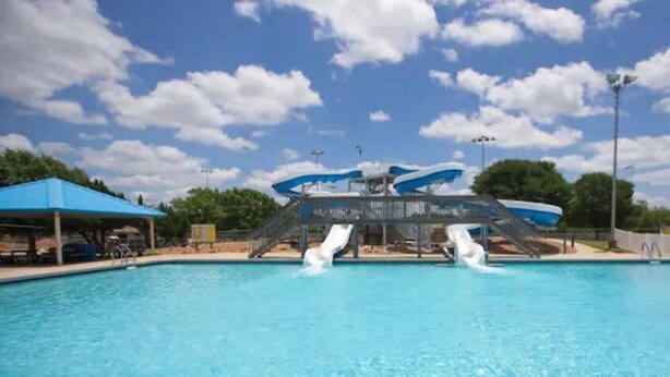 A swimming pool with two slides and a covered seating area. - 8min Texas A&M, 1 King Beds, firepit, GriddleGrill (College Station)