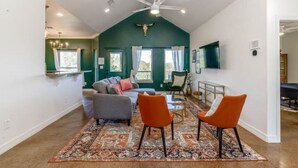 Un salon spacieux avec un plafond haut, une grande fenêtre et un ventilateur de plafond.