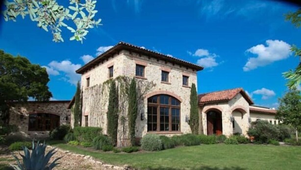 Un bâtiment en pierre, doté d’un toit en tuiles, de fenêtres en arc de cercle et d’un jardin bien entretenu.