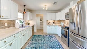 A modern kitchen with white cabinets, stainless steel appliances, and a patterned rug. - River, Wine, Hot Tub, 2 King Beds, Large backyard (Blanco)