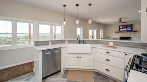 A modern kitchen with white cabinets, a dishwasher, and a large window overlooking a scenic view. - 5 kings, 3 acres, lake view, cabana, firepit/stars (Buchanan Dam)
