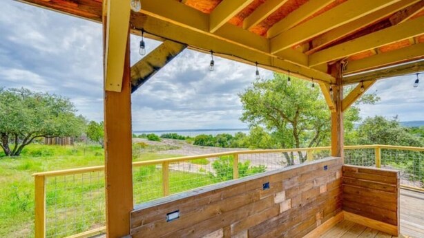 A wooden deck with a view of a grassy area and trees. - 5 kings, 3 acres, lake view, cabana, firepit/stars (Buchanan Dam)