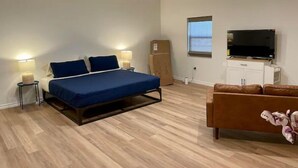 Un dormitorio con cama, lámparas de noche, ventilador de techo, televisor, armario y ventana.