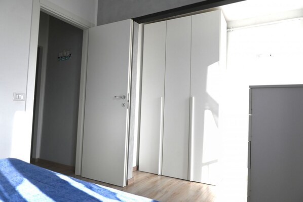 A room with a bed, a wardrobe, and a door leading to another room.