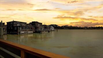 A waterfront property with a wooden deck, a staircase leading to a second floor, and a view of the water.