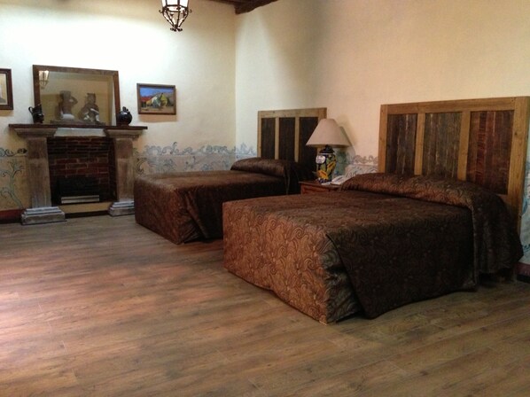 A bedroom with two single beds, a fireplace, and a nightstand with a lamp. - Hotel Travel  (Puebla)