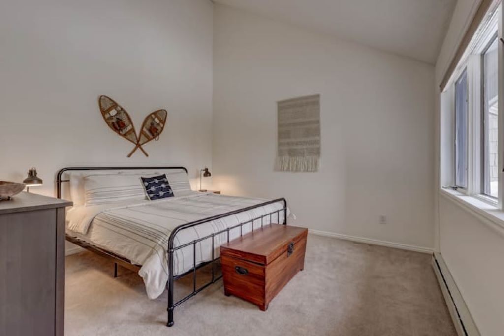A bedroom with a bed, a wooden chest, a wall-mounted decoration, and a window.