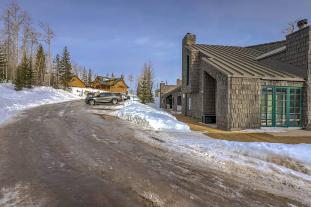 Una carretera nevada con un edificio a la derecha y un albergue al fondo.