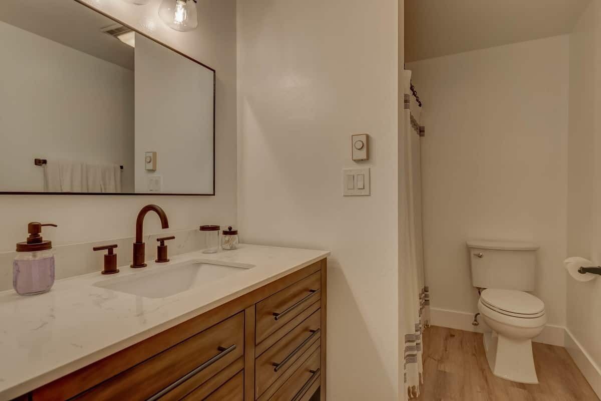 A bathroom with a white sink, wooden vanity, and a toilet.