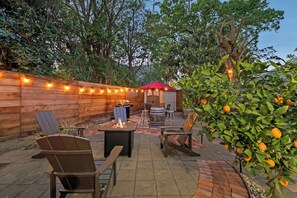 An outdoor patio with a fire pit, seating, and a fruit tree.