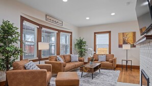 A modern living room with two sofas, a coffee table, and a fireplace. - Eastown Luxe (Grand Rapids)