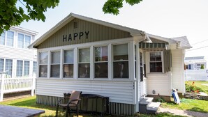A small, single-story house with a 'HAPPY' sign on the front, a front porch, and a picnic table. - Sept 5-12 cancellation, reduced rates! Walk to beach in Wells, 1 dog welcome! (Wells)