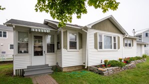 A single-story house with a front porch, a small garden with flowers, and a brick pathway leading to the entrance. - Sept 5-12 cancellation, reduced rates! Walk to beach in Wells, 1 dog welcome! (Wells)