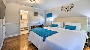 A bedroom with a large bed, a nightstand, a dresser, a mirror, and a wall-mounted TV. - Bay Shore Vacation Rental w/ Shared Yard! (Bay Shore)
