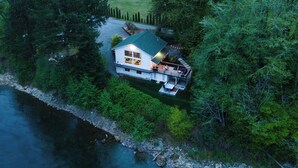 Ein Haus mit grüner Dachbegrünung, umgeben von dichtem Wald, in der Nähe eines Gewässers.