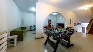 Amplia sala de estar con una mesa de futbolín, un sofá verde y una mesa de centro de madera.