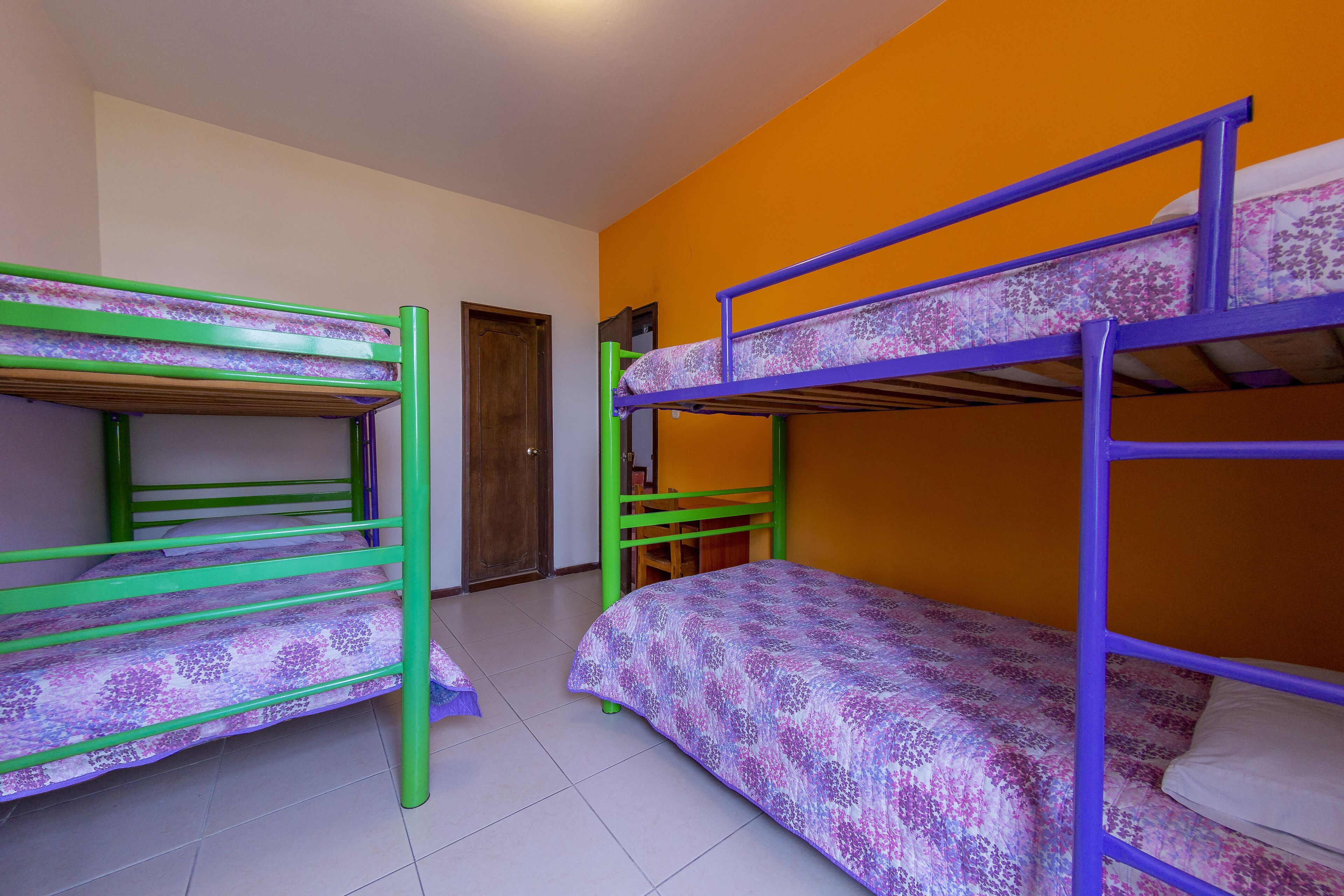 Ein Schlafsaalzimmer mit Etagenbetten, einer Tür und orangefarbenen Wänden.
