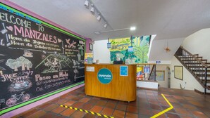 Un mostrador de recepción con una pared de pizarra que muestra mensajes de bienvenida y horario de atención.