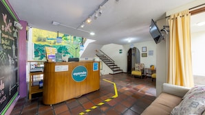 Zona de recepción de un hotel con un mostrador de madera, un mapa en la pared y una escalera que sube.