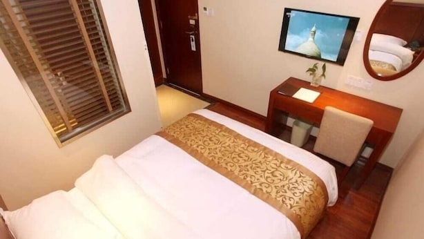 A hotel room with a bed, a desk, a chair, a television, and a window with blinds. - Greentree Inn Shanghai Songjiang Wanda Plaza Rongmei Road Express Hotel (Shanghai)
