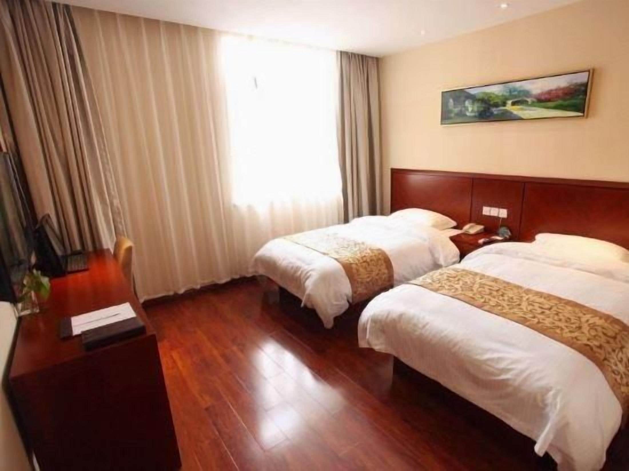 Ein Hotelzimmer mit zwei Betten, einem Holztisch, einem Stuhl und einem Gemälde an der Wand.
