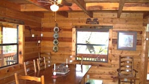 L’intérieur d’un chalet en bois, avec une table à manger, des chaises, un banc et une pancarte « Bienvenue ».