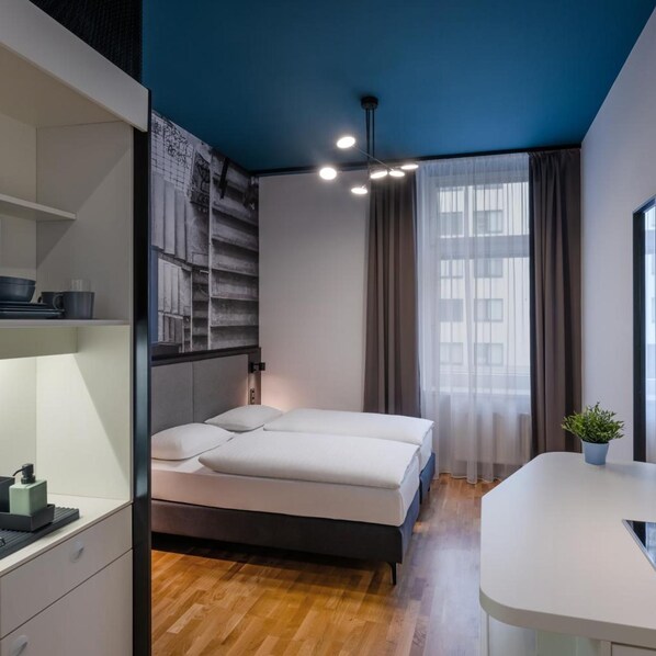 A modern bedroom with a bed, a desk, and a window with curtains. - Deans Home Budapest (Budapest)