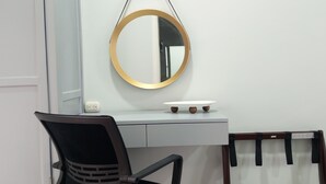 Une pièce comprenant un bureau, une chaise, un miroir rond et une petite table à la surface blanche.