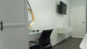 Une chambre d’hôtel avec un lit, un bureau et une chaise, un téléviseur fixé au mur et une porte.