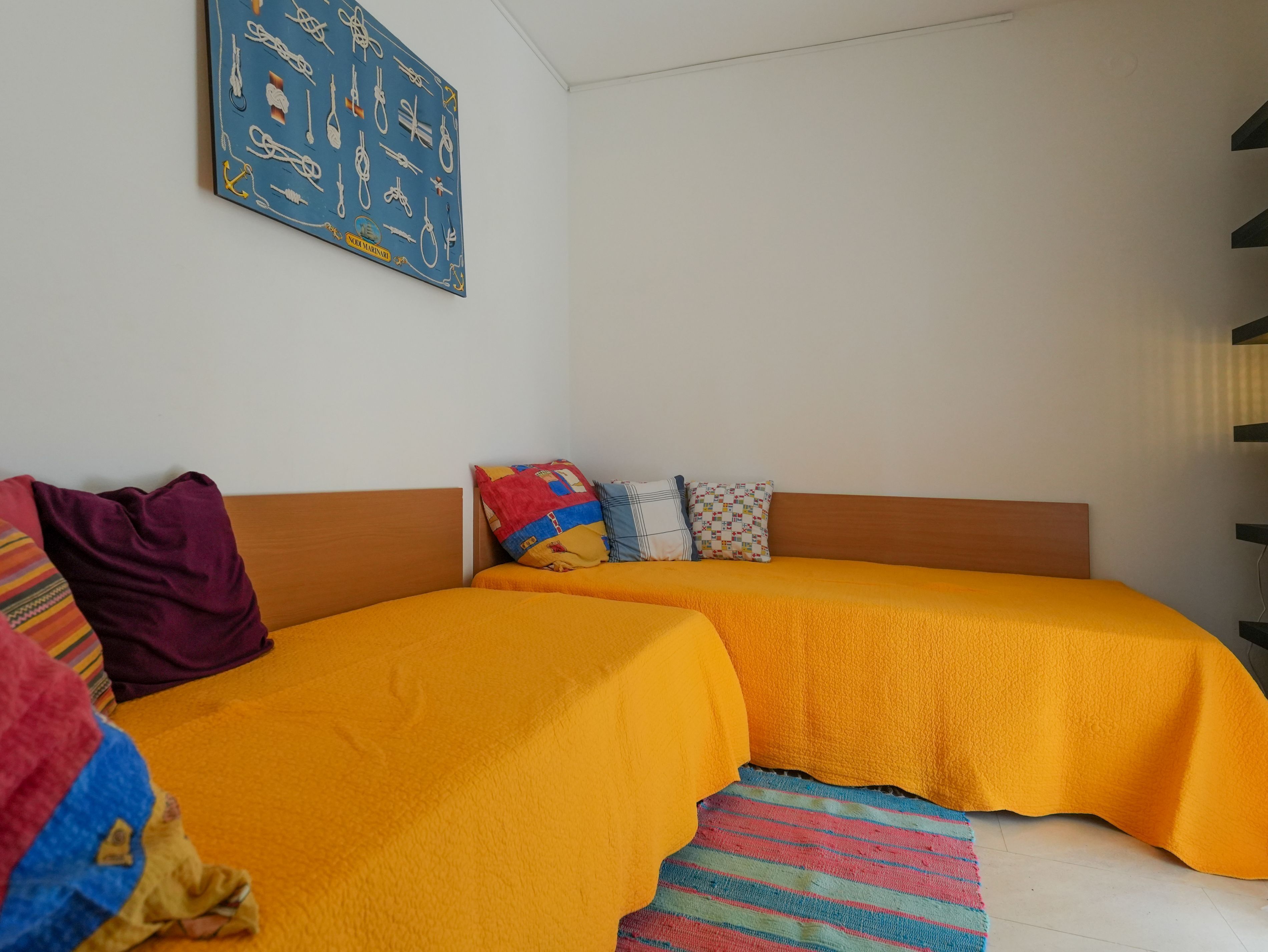A bedroom with two beds, a colorful quilt, and a wall art piece.