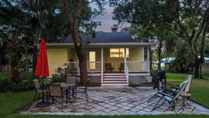 Una casa con porche, mobiliario exterior y una parrilla.