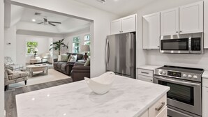 Una cocina moderna con armarios blancos, electrodomésticos de acero inoxidable y encimera de mármol.
