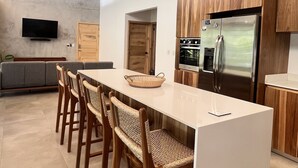 Een moderne keuken met houten kastjes, een roestvrijstalen koelkast en een groot eiland met stoelen.