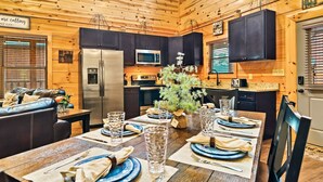 A cozy cabin interior with a dining table set for four, a refrigerator, a microwave, and a kitchen counter. - Pet Friendly! Private Pool, Mini Golf, Views! (Pigeon Forge)