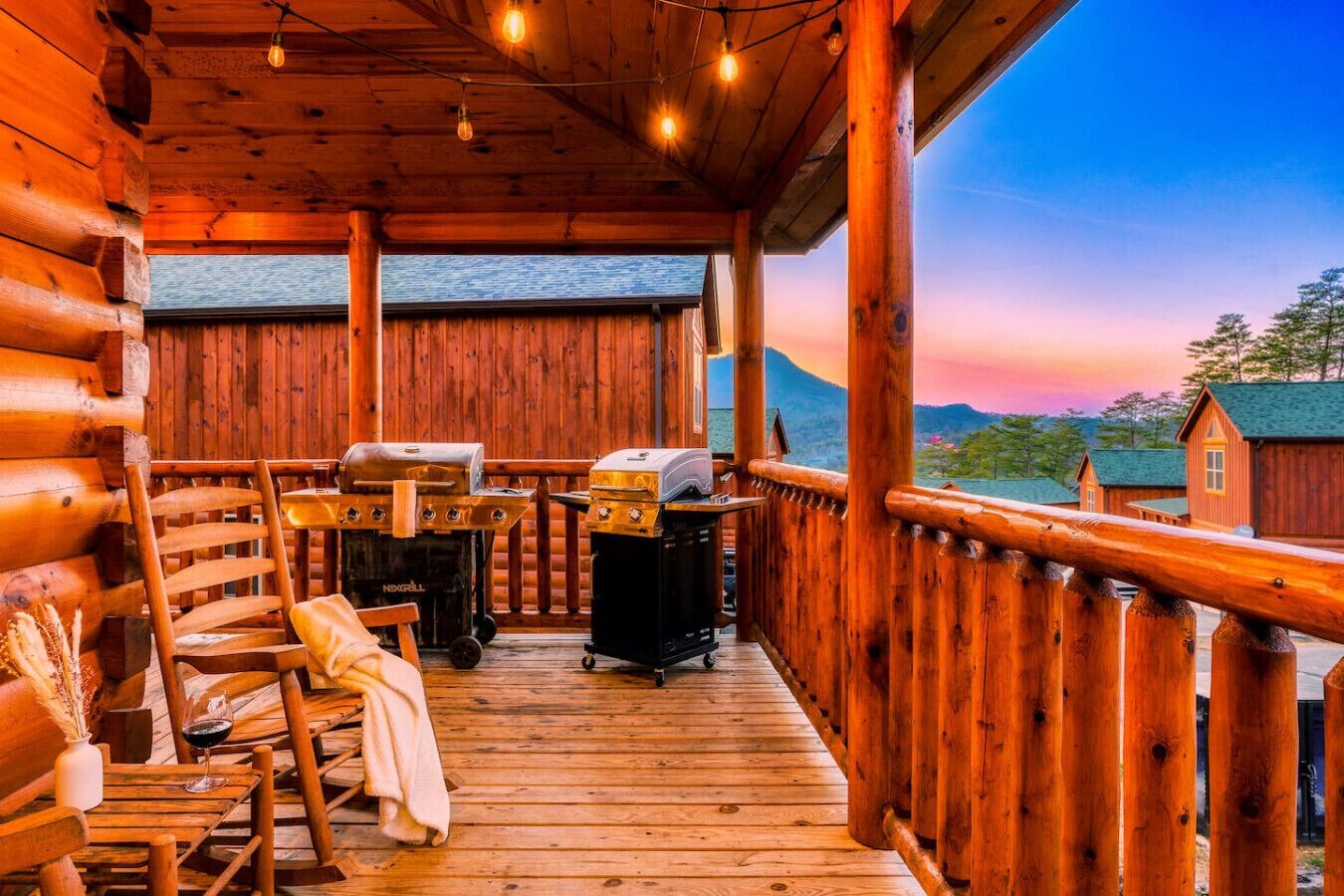 En træhytte med veranda, grill, stol og bord.