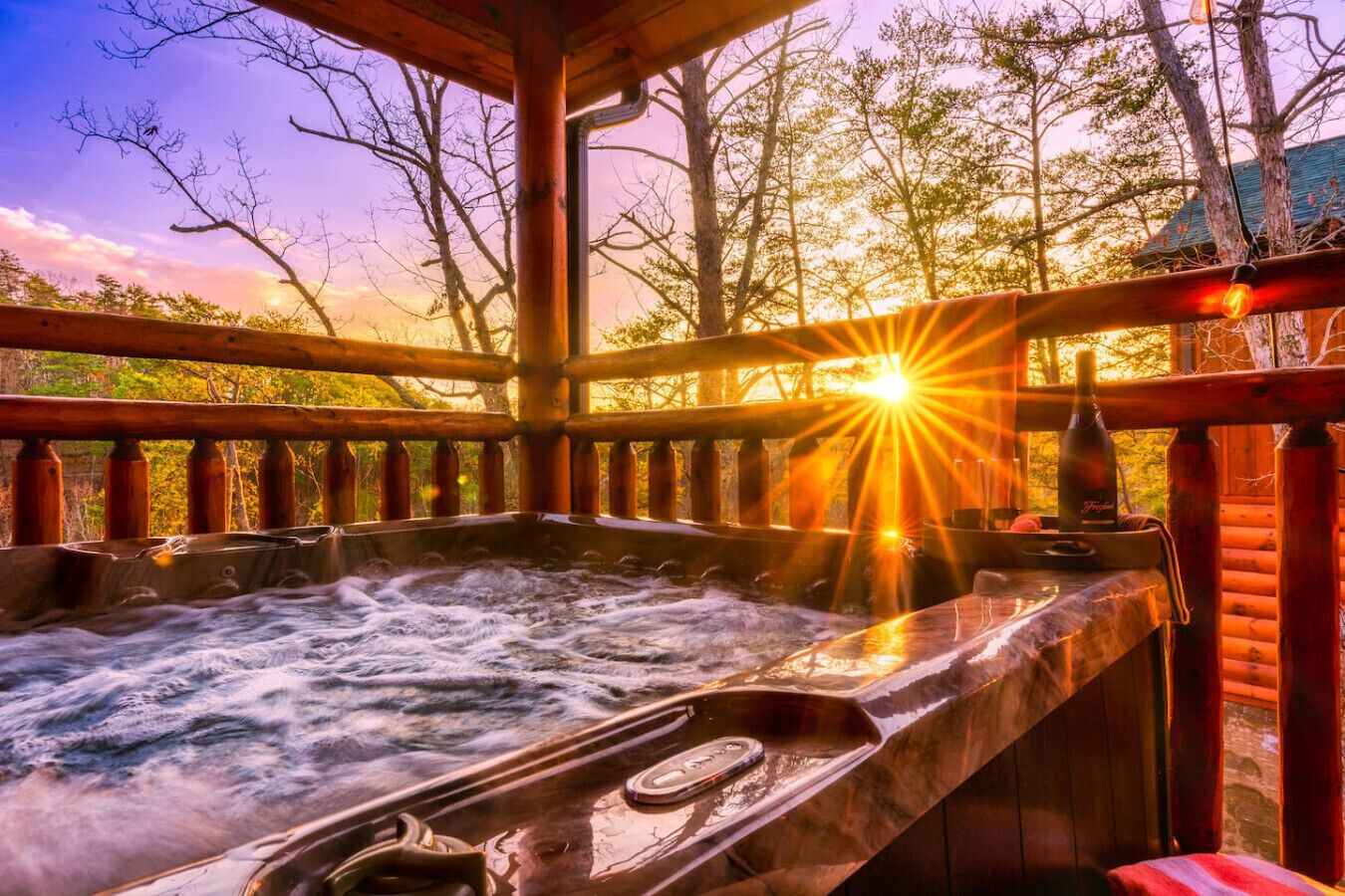A hot tub with a wooden deck and a sunset view.