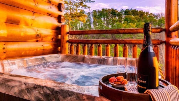 A wooden cabin with a hot tub, a bottle of Freixenet champagne, and macarons on a tray. - Pet Friendly! Private Pool, Mini Golf, Views! (Pigeon Forge)