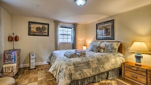 A bedroom with a bed, bedside table, lamp, heater, window, and two framed pictures on the wall. - 3 Mi to NIH! Spacious Bethesda Apt w/ Yard (Bethesda)