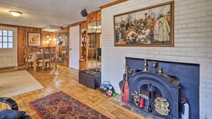 A cozy living room with a fireplace, a dining area with a table and chairs, and a large painting on the wall. - 3 Mi to NIH! Spacious Bethesda Apt w/ Yard (Bethesda)