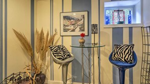 A room with striped walls, a framed picture, a vase with dried plants, and two chairs with zebra-patterned cushions. - 3 Mi to NIH! Spacious Bethesda Apt w/ Yard (Bethesda)