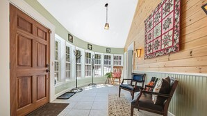 Un'ampia sala con una porta in legno, ampie finestre e un pannello decorativo trapuntato.