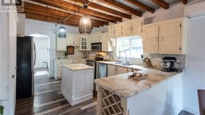 A spacious kitchen with white cabinetry, a central island, and a wooden ceiling. - Private house/large hottub/sauna & optional "Adult/Red room" (Rothesay)