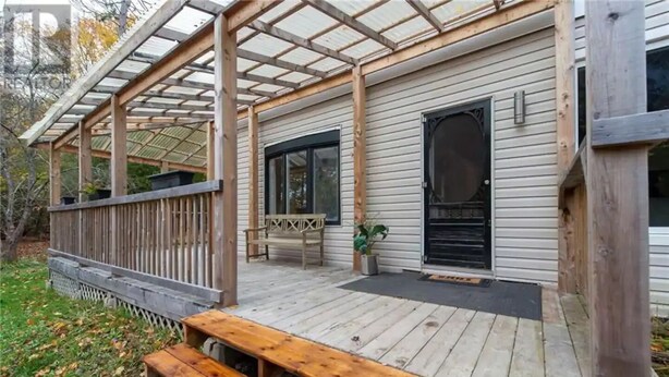 A wooden deck with a covered porch, a bench, and a door. - Private house/large hottub/sauna & optional "Adult/Red room" (Rothesay)