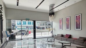 A modern lobby with a glass partition, a sofa, a coffee table, and framed artwork on the wall. - Rasa Sayang at The Loft Imago (Kota Kinabalu)