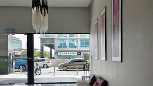 A modern hotel lobby with a glass table, a sofa with cushions, and framed artwork on the wall. - Rasa Sayang at The Loft Imago (Kota Kinabalu)
