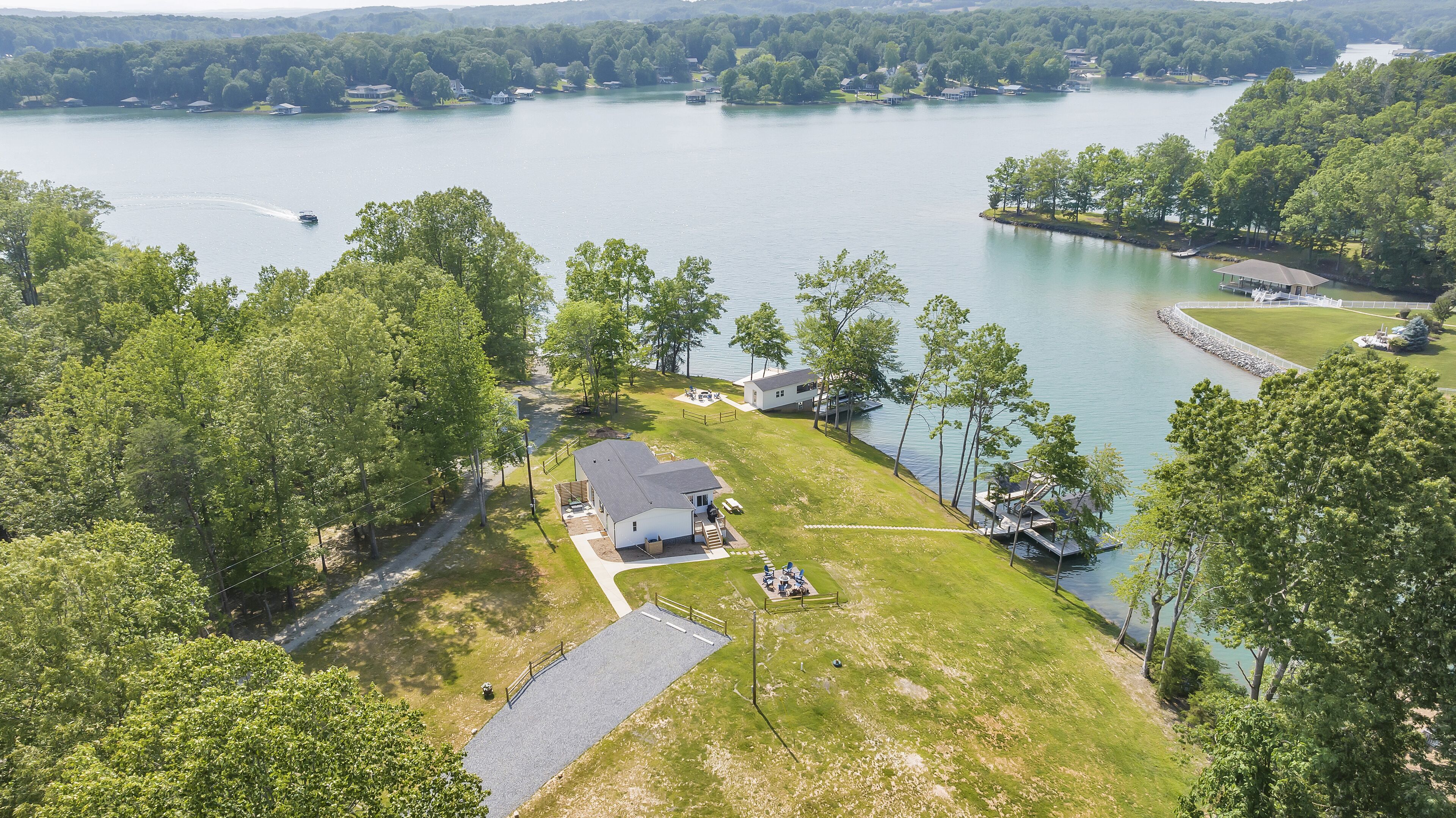 An aerial view of a lakeside property with a house, dock, and surrounding greenery.