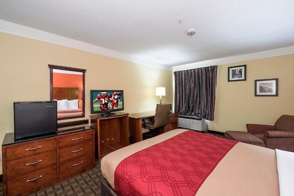 Una habitación de hotel con cama, escritorio, televisor, cómoda y una silla.