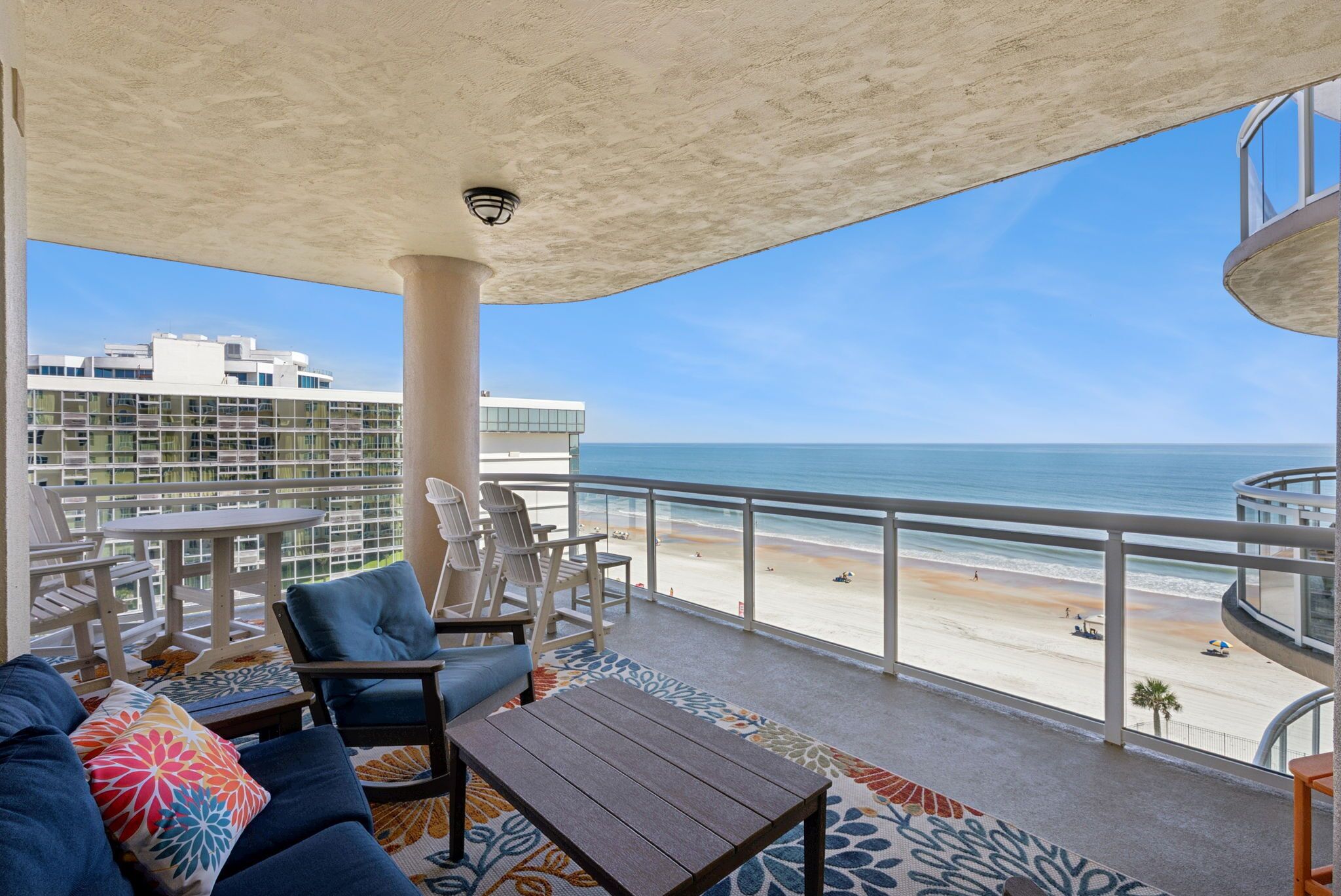 Een balkon met uitzicht op het strand, voorzien van stoelen en een tafel.